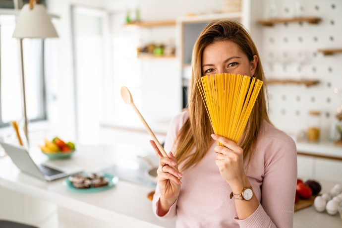 Happy joyful woman holding long pasta ready to cook. Healthy food concept.